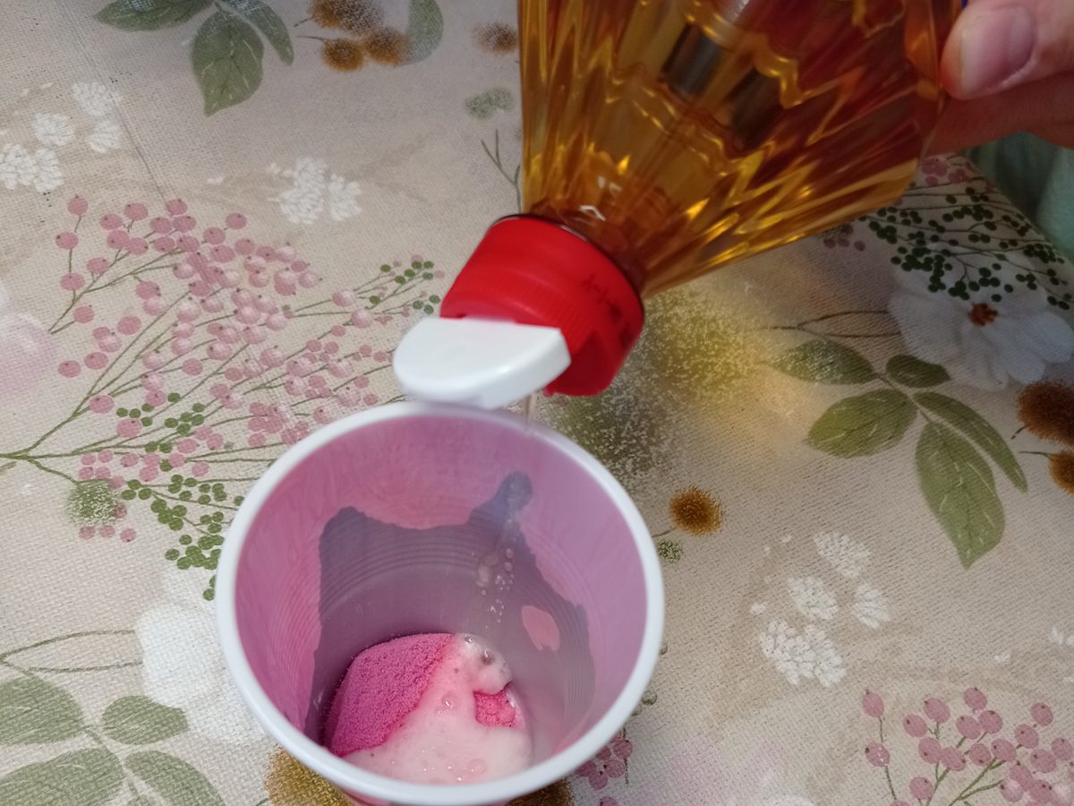 Manos echando líquido con purpurina en un vaso