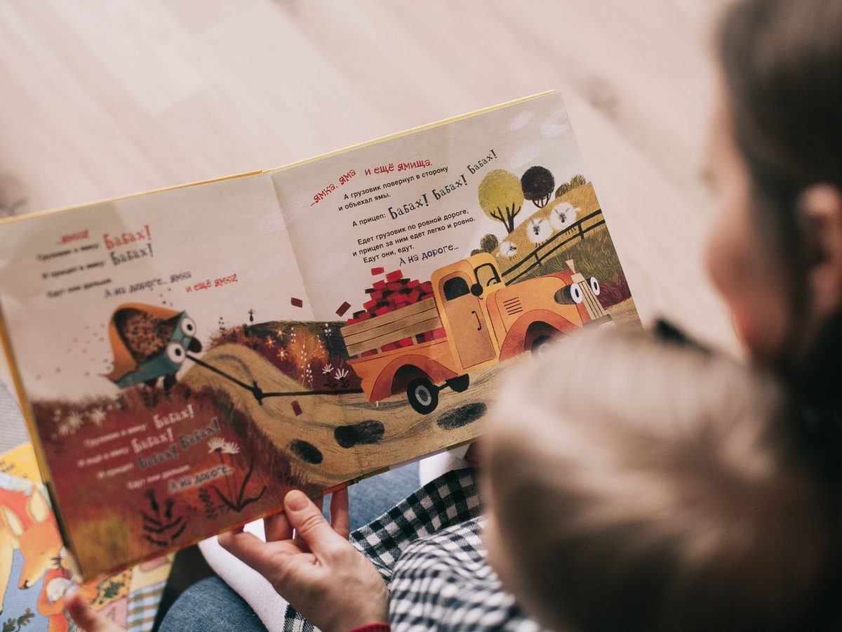 Adulto leyendo un cuento ilustrado a un niño pequeño