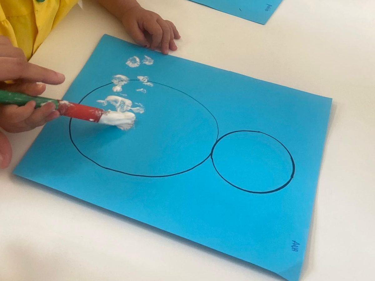 Manos pegando algodón sobre círculos dibujados en papel azul
