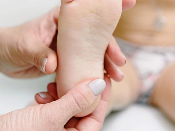 Manos de un adulto masajeando el pie de un bebé