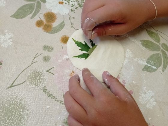 Manos presionando una hoja sobre masa blanca
