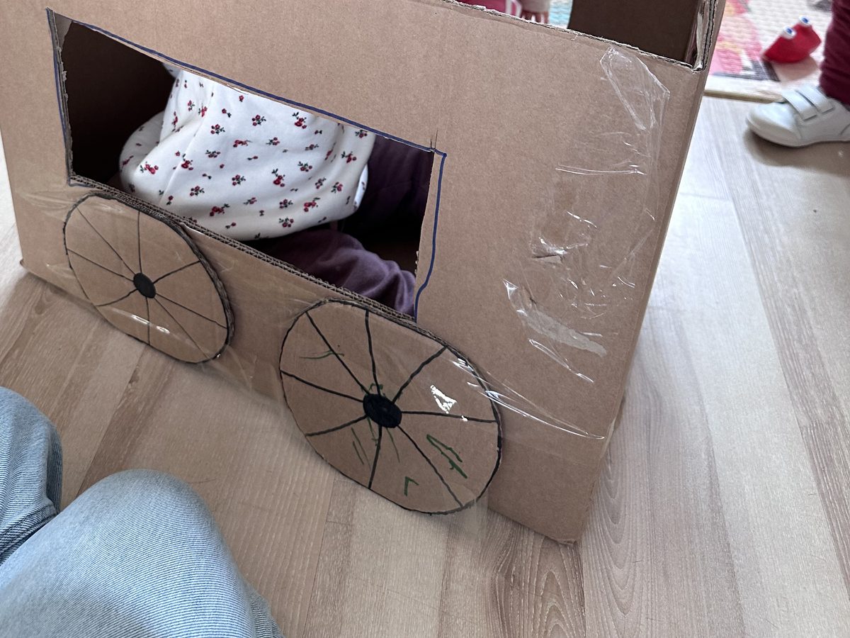 Caja de cartón convertida en vehículo con ruedas