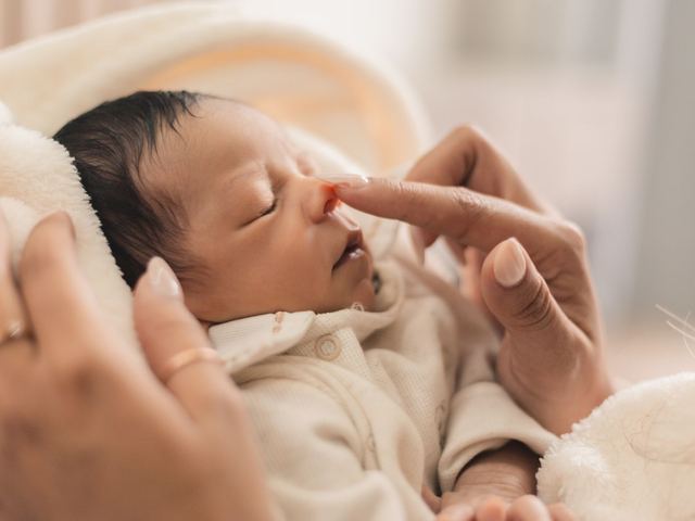 Pies de un bebé pequeño asomando bajo una manta de punto