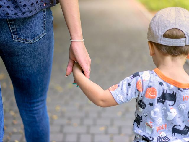 Mano de un adulto sujetando la mano pequeña de un niño en la puerta de un aula